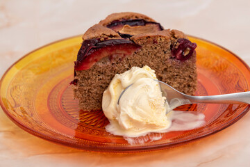 cake with plum and vanilla ice cream on orange plate