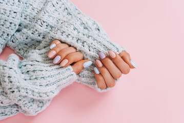 Stylish fashionable female manicure. Beautiful hands of a young woman on a pink and blue background.