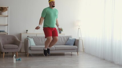 Overweight chubby man jumping with skipping rope, practicing sports workout at home interior, tracking shot