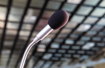 Nahaufnahme eines Mikrofons seitlich aus der Froschperspektive in einem Konferenzsaal, Hörsaal...