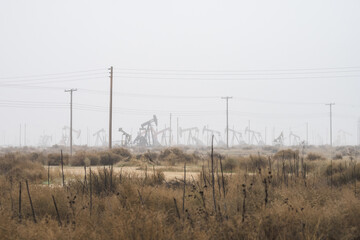 Pumpjacks extract oil from a field on a foggy day