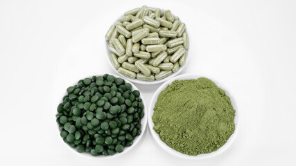 three type of superfoods chlorella or spirulina - powder, tablets, capsules, white background