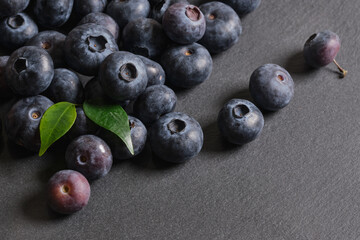 Fresh blueberries are scattered on a dark stone background. Products for a healthy diet. A source of vitamins. 