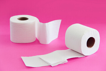 white toilet paper in a roll on a pink background