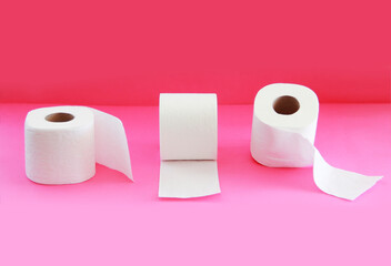 white toilet paper in a roll on a pink background