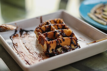 Waffles sprinkled with chocolate in a white plate
