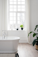 Bathtub against window in white modern bathroom