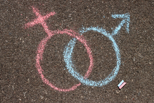 male and female gender symbols mars and venus are drawn in chalk on the asphalt