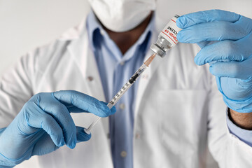 covid-19 coronavirus Vaccination concept in hand of doctor glass vaccine jar ampoule syringe . White robe and gloves