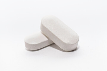Close-up of two white pills tablet capsules on white background