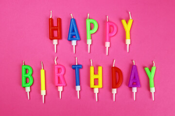 Colorful happy birthday candles on a pink pbackground