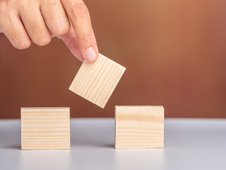 Close-up of hand holding empty wooden block on white table with a vintage background. Space for text