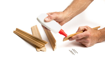 a craftsman putting glue onto wood molding to make a picture frame isolated on white