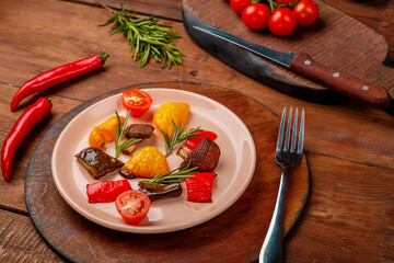 Antipasta on a plate on a wooden table next to vegetables on wooden boards.