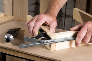 male hands using a combination square to check that the woodworking project corners are square