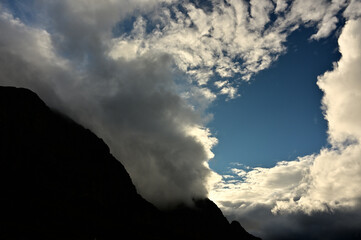 Silhouette of Western Cape mountains with a bright blue sky specked with dramatic clouds