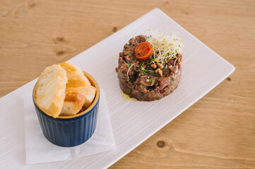 Tartar de ternera acompañado de tostadas de pan blanco en un restarante de categoría
