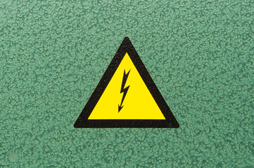 A triangular sign "high voltage" on a green metal background