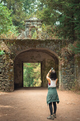 Fototapeta na wymiar Young woman from behind taking a photo to the arches of the old road. Young traveler takes a photo of the landscape. Tourism and vacation concept. Travel concept
