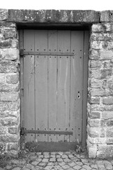 black and white photo of a medieval wooden door as access to a medieval old castle