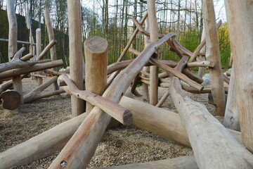 Climbing frame made of tree trunks on a playground with gravel stones in the forest