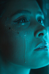 crying woman with sparkles makeup and light cyan color