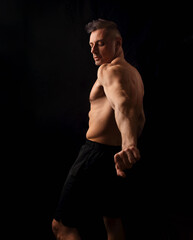 Obraz na płótnie Canvas Powerful strong sport man with muscular bodybuilder looking and holding his arm muscle tension on black dark background. Closeup