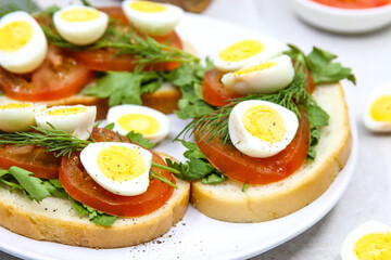 Fresh toast sandwiches with quail eggs, tomatoes and green herbs. Closeup. Top view. 