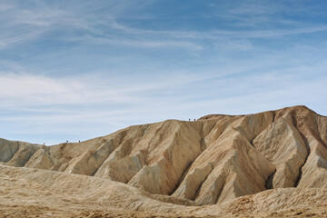 A family hike from Zabriskie Point in Death Valley national park in california. Huge sand dunes, terracotta mountains and hazy horizons are shining against clear blue sky in the midday sun.
