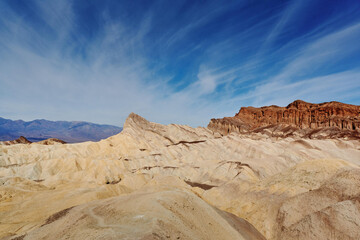 Fototapeta premium A family hike from Zabriskie Point in Death Valley national park in california. Huge sand dunes, terracotta mountains and hazy horizons are shining against clear blue sky in the midday sun.