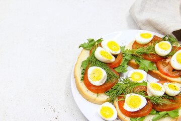 Fresh toast sandwiches with quail eggs, tomatoes and green herbs. Closeup. Top view. Copy space.