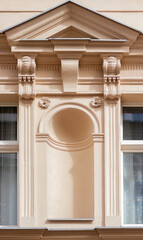 An empty niche in a classic style with a tympanum and pilasters on the facade of a town house