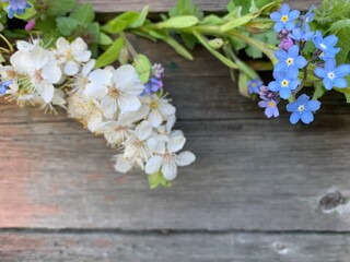 Fototapeta na wymiar Bright blue forget-me-nots and white flowers on a wooden background. Copy space. Place for your text.