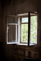Fototapeta na wymiar Dirty old open window with broken glass in abandoned house in ghost town Pripyat, Chernobyl Exclusion Zone, Ukraine. Vertical photo