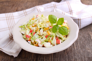Salad of cabbage with grains corn and crab sticks in a plate on an old background. © Ustinova