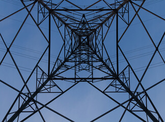 An electricity pylon shot from underneath in perfect symmetry against a blue sky