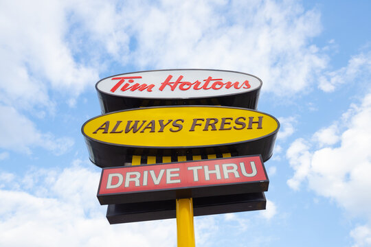 Hamilton, Ontario, Canada - April 2020: Sign showing Tim Hortons fast food restaurant logo and slogan with sky background