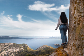Naklejka premium young woman standing on a cliff in front of a bay