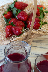 Strawberry in basket and on table on wooden background, strawberry juice in jug
