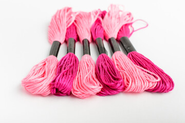 Many mixed vivid pink sewing threads for embroidery isolated on a white table, top view or flat lay of textile materials.