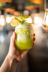 Lemonade or mojito cocktail with lemon and mint, cold refreshing drink or beverage with ice with hand