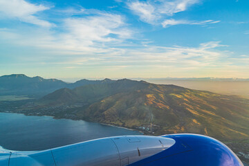 View of the tropical island of O'ahu from above over wing during golden hour