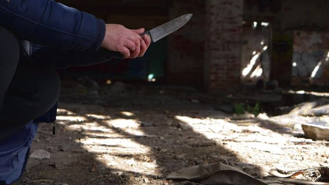 Criminal with knife waits in the shadows of derelict building 