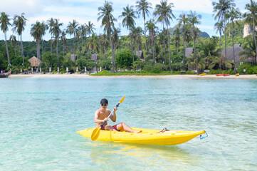 A young sporty man kayaking at the ocean in a sunny day