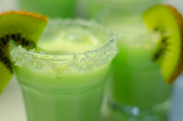 Fruit shot drink based on alcohol, liqueur and cream, decorated with green sugar crystals and a slice of fresh kiwi