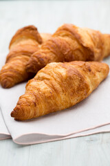 Tasty buttery croissants on old wooden table.