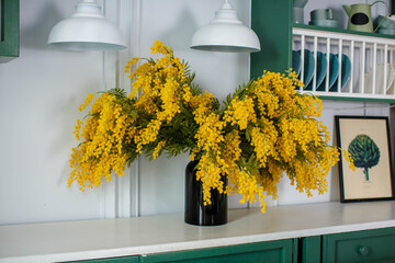 a vase of mimosa in a mint colored kitchen