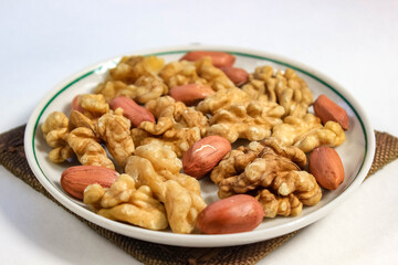 Peeled walnuts and peanuts on a saucer close-up.