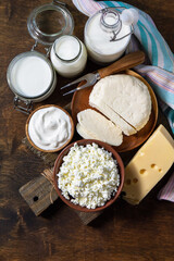 Set of different dairy organic products (milk, sour cream, cottage cheese, yogurt and butter) on a rustic wooden countertop. Top view flat lay. Copy space.