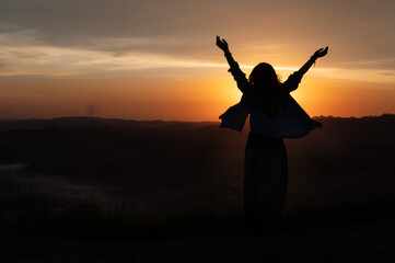 girl silhouette wih arms up with and a beautiful sunset